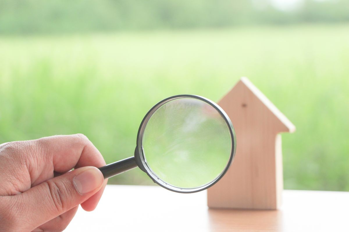 Magnifying glass with mini wood house model on green background, Home inspection concept or find new homes